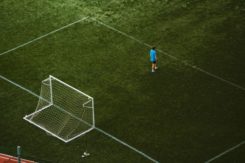 Aerial view of a goal and player on a grass pitch